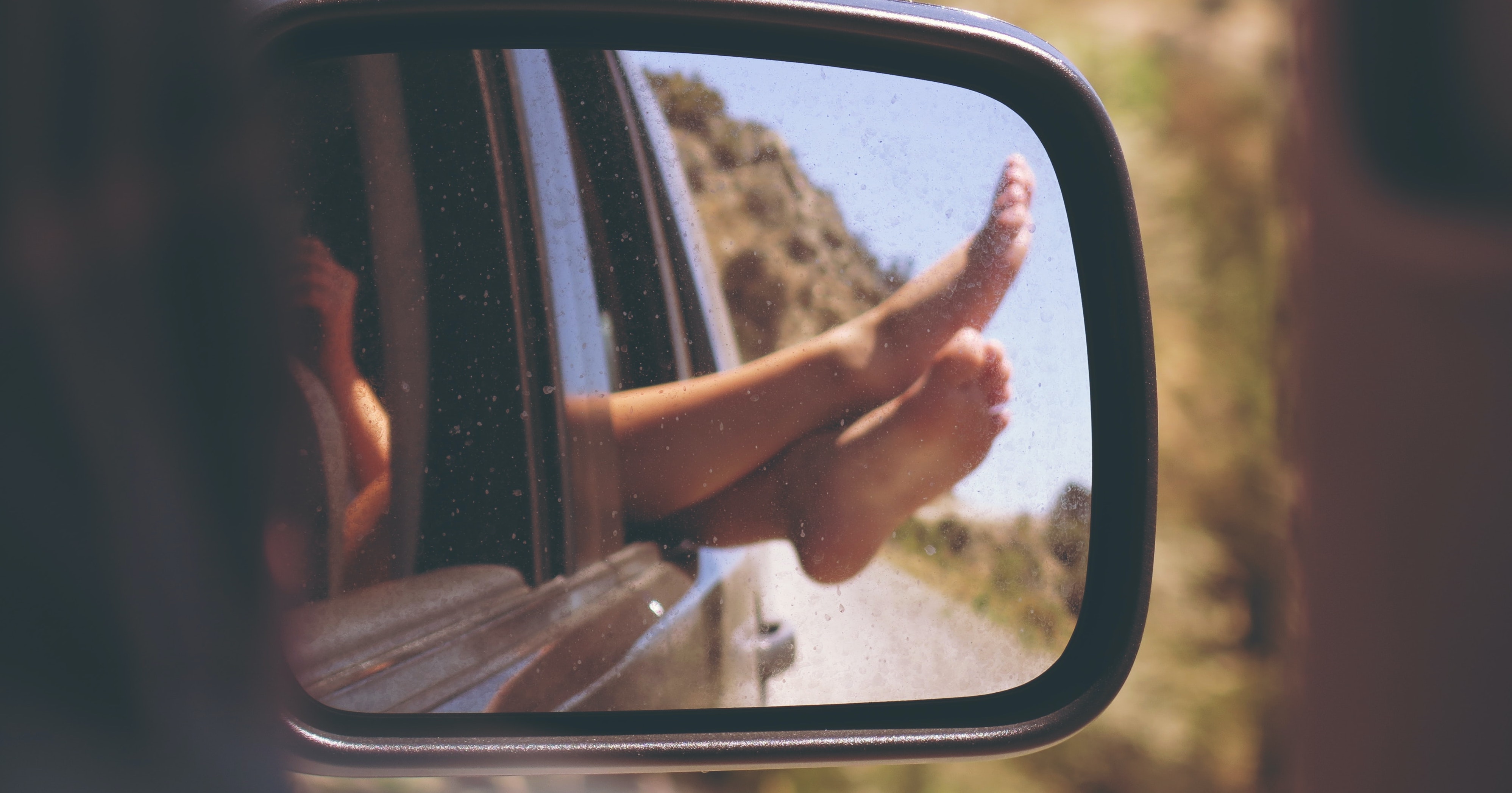 Feet out the window and car wing mirror